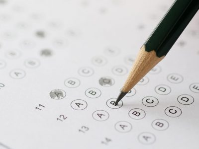 Woman solving tests and writing in pencil on paper closeup. Exam testing concept